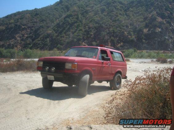 red SUV with off-road tires on a dirt road, mountains in background