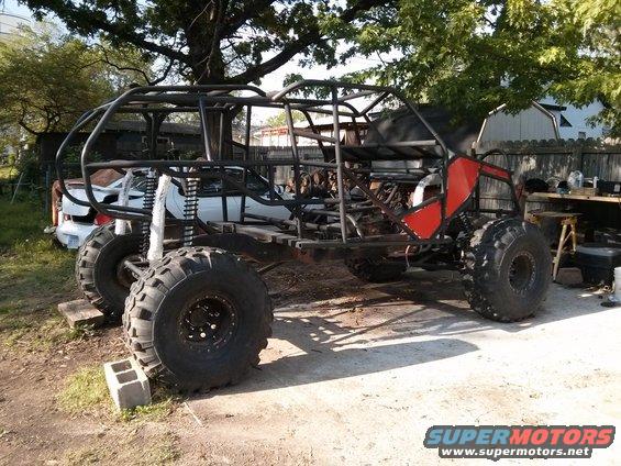 Custom buggy frame with large tires and red panels, side view