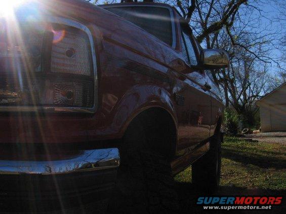 Red pickup truck, front quarter view, sun glare on headlight