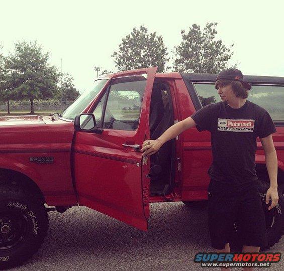 1992 Ford Bronco, red, driver's door open, person standing beside it