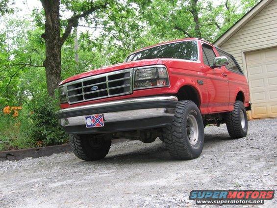 Red 1992 Ford Bronco parked on gravel in front of a garage