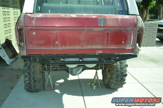 Red SUV rear view, missing taillights, on jack stands with large off-road tires