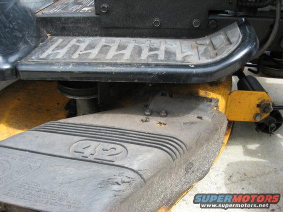Lawn mower deck with 42 inscribed, showing yellow mounting bracket and black textured step