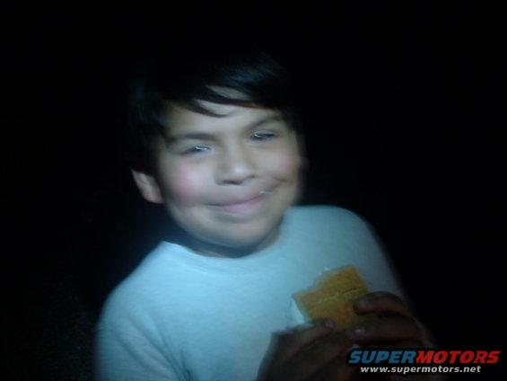 Boy eating a s'more at night