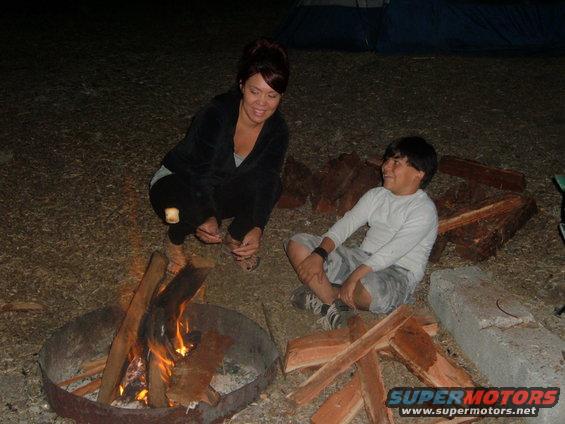 Two people roasting marshmallows over a campfire at night