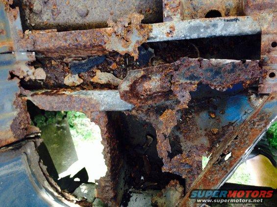Heavily rusted frame section with holes showing blue paint underneath