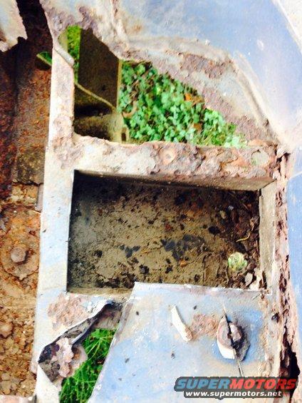 Rusted metal frame with holes showing grass and dirt