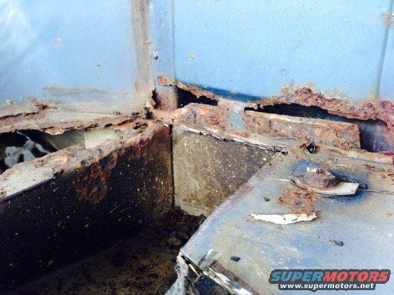 close-up of heavily rusted metal structural components, likely from a vehicle's undercarriage or frame