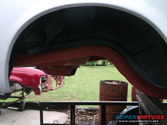 Undercarriage and wheel well of a vehicle, with a red car front visible