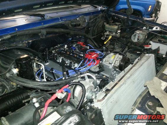 Engine bay with new MSD distributor and blue spark plug wires. Another vehicle is visible in the background
