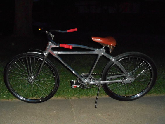 Custom bicycle with silver frame, brown seat, and red grips