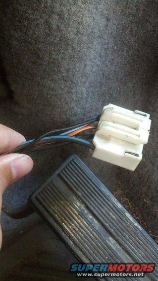 Close-up of a vehicle's wiring harness connector and a black ribbed pedal