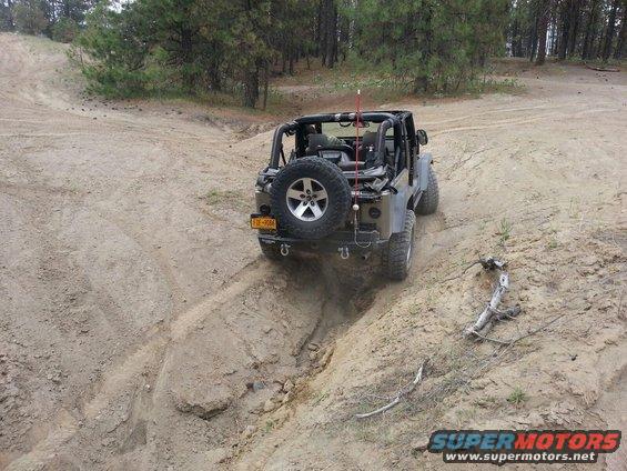 2005 Jeep Wrangler driving down a steep dirt path, spare tire mounted on the back