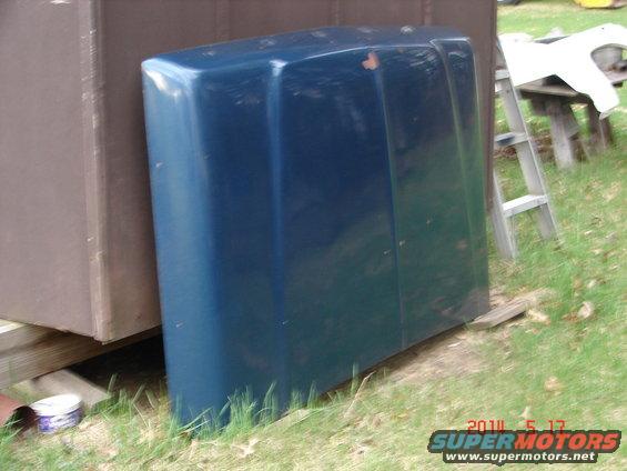 blue vehicle hood leaning against a brown structure