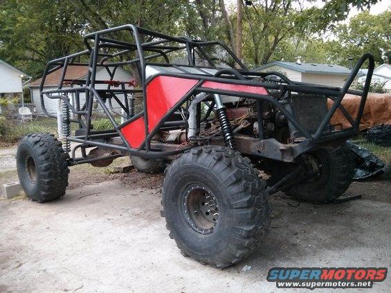 Custom off-road buggy with a roll cage, large tires, and red body panels