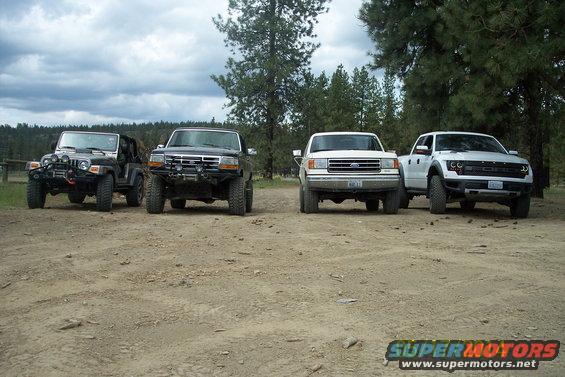 Jeep, old Ford truck, newer Ford truck, and a Ford Raptor parked on dirt