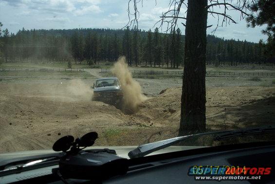 Silver Ford Bronco kicking up dust on a dirt road