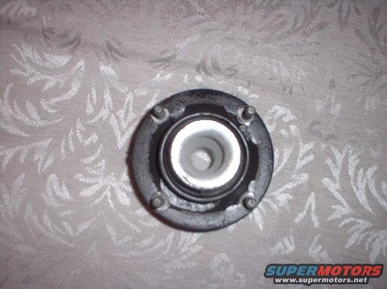 Strut mount with four bolts on a patterned fabric background. Text 'SUPERMOTORS' is visible