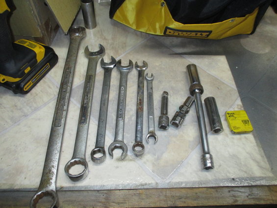 Assortment of wrenches, sockets, and a power drill battery