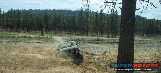 Truck driving off-road, kicking up dust on a dirt track