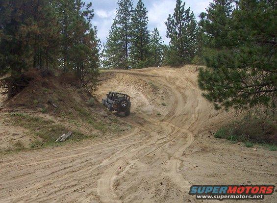 Black Jeep Wrangler driving up a sandy hill, 2005 model