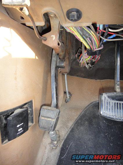 1988 Ford Bronco interior footwell showing brake, clutch, and gas pedals, plus hood release lever and exposed wiring harness