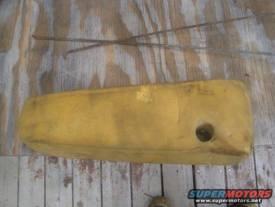 Yellow foam padding with a circular hole, lying on a wooden surface. Two rusty metal rods are crossed above it