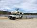 1997 Dodge 3500 - A white 1997 Dodge 3500 pickup truck equipped with a camper shell is parked at a campsite next to a lake.