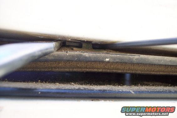 Close-up of tailgate torsion bar mechanism with dust and debris