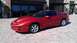 1976 Pontiac Trans Am - This red Pontiac Firebird is parked on a brick patio outside a building with large windows.