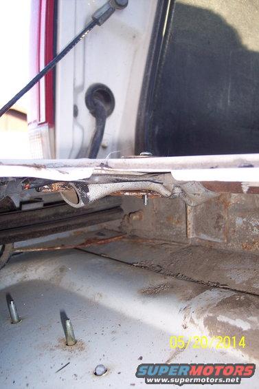 Rusty tailgate torsion bar mechanism with visible bolts and cables