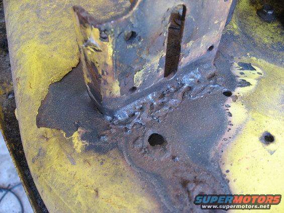 Close-up of rusted yellow metal with rough welds and holes