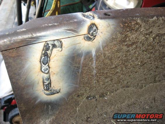 Metal part with crude welds and rust. A yellow strap is visible above