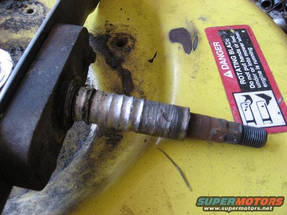 Close-up of a mower deck spindle with a danger sticker