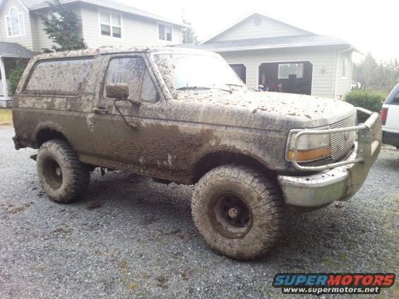 Mud-covered SUV, 3/4 front view, showing grille and tires