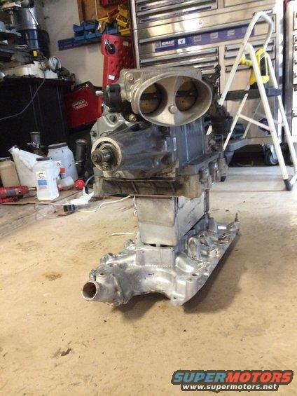 Engine with a dual-barrel supercharger mounted on a stand in a garage