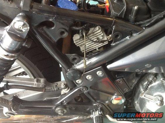Motorcycle engine and frame with visible wiring and a blue cap