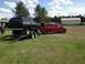 1978 Ford Bronco - A black 1978 Ford Bronco is loaded onto a trailer, towed by a red Ford F-350 Super Duty, in an outdoor setting.