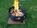 1978 Ford Bronco - A black, octagonal fire pit with decorative horse cutouts sits on brick pavers in a grassy yard, with a fire burning inside.