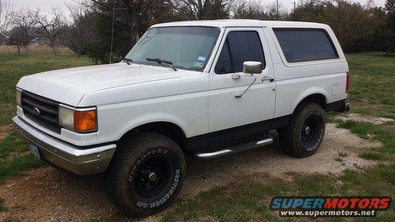 White Ford Bronco parked on dirt and grass