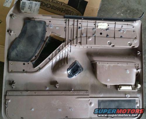 Brown interior door panel with speaker cutouts and mounting holes. A black handle is attached