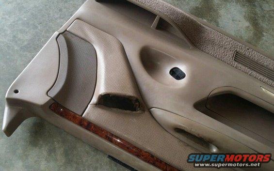 Tan interior door panel with wood trim and speaker grille