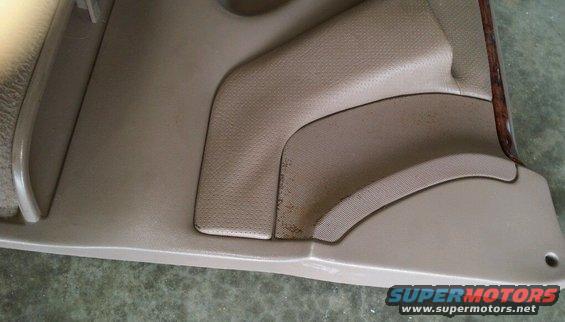 Tan interior door panel with textured inserts and a wood trim piece