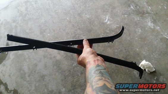 Hand holding two black plastic door trim pieces against a concrete floor