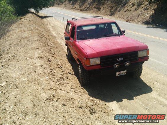 Red 1988 Ford Bronco parked on dirt road, 3q-front view