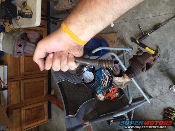 hand holding exhaust pipe section with a rusty flange