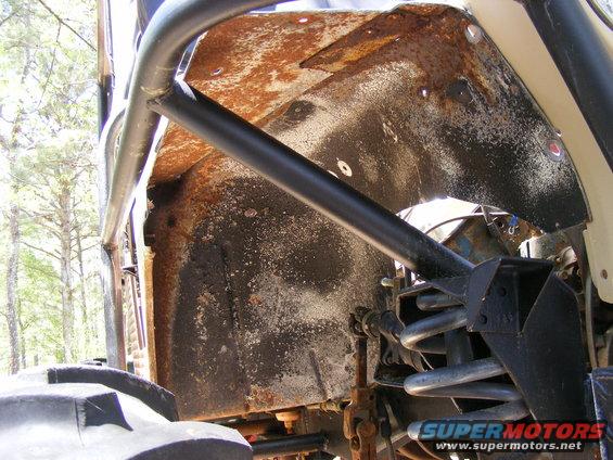 Close-up of rusty wheel well and suspension components on a modified off-road vehicle