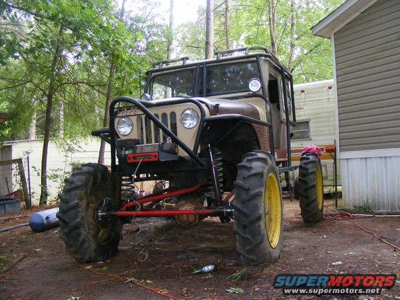 Modified off-road vehicle with large tires and roll cage, front view