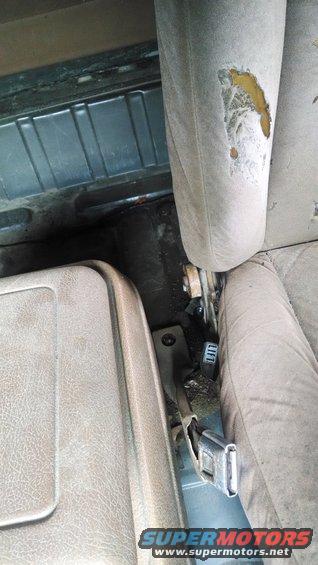 Worn interior seats and floor of a vehicle, with visible seatbelt buckle and a 'LIFT' label on a lever