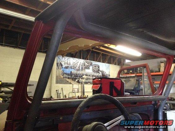 1985 Jeep CJ7 interior showing roll cage, steering wheel, and red tool bag